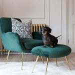A light, bright room is dressed with a dark green velvet chair and .