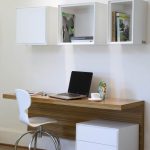 modern study space with a wall mounted desk and open box shelves .