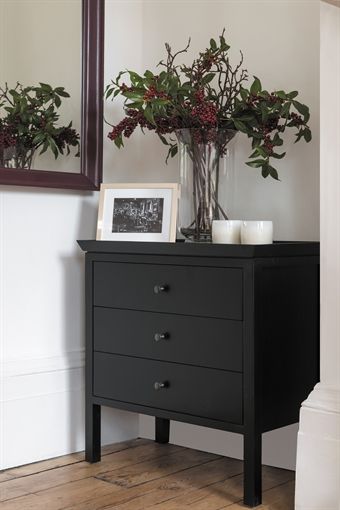 A simple black chest of drawers made from solid timber with a .