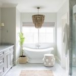 Gorgeous white and gray bathroom is illuminated by a brown beaded .