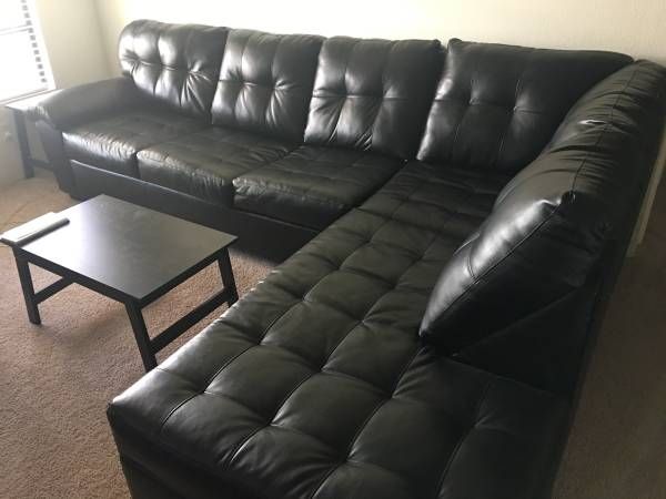 A slightly used, black leather, 2 piece sectional couch .